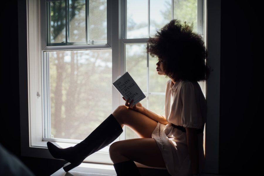 woman sitting on window reading book