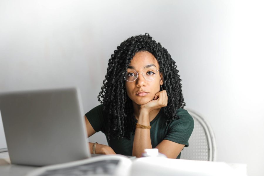 serious ethnic young woman using laptop at home long-term unemployment